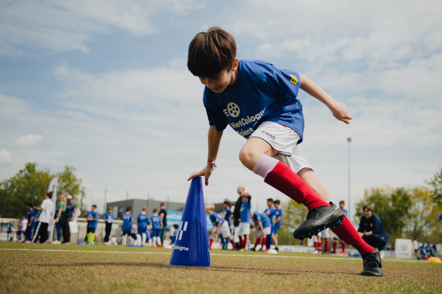 Jugendfußballer Ein junger Fußballer im NetCologne-Trikot mit NetCologne-Logo und Autogrammen, der einen Fußball in den Händen hält.